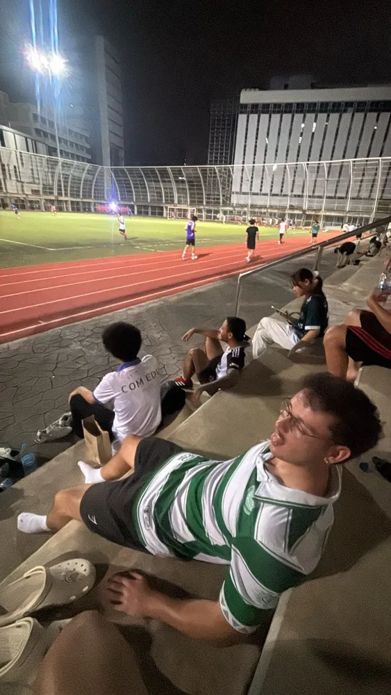 Friends sitting beside the football field at night