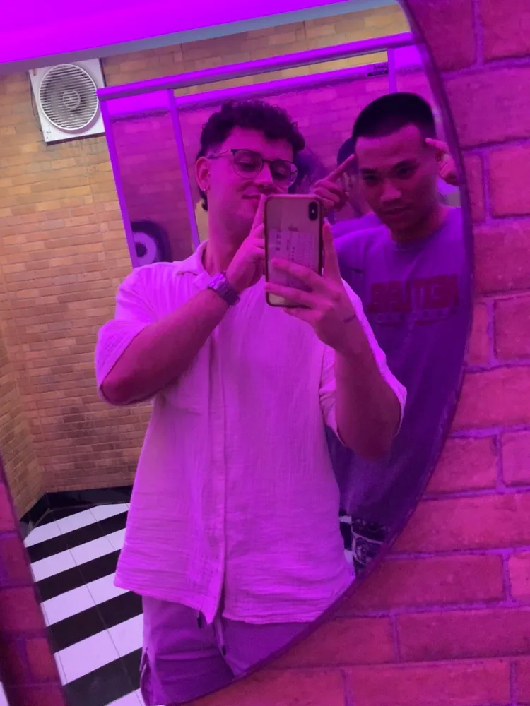 Two friends posing under purple lights