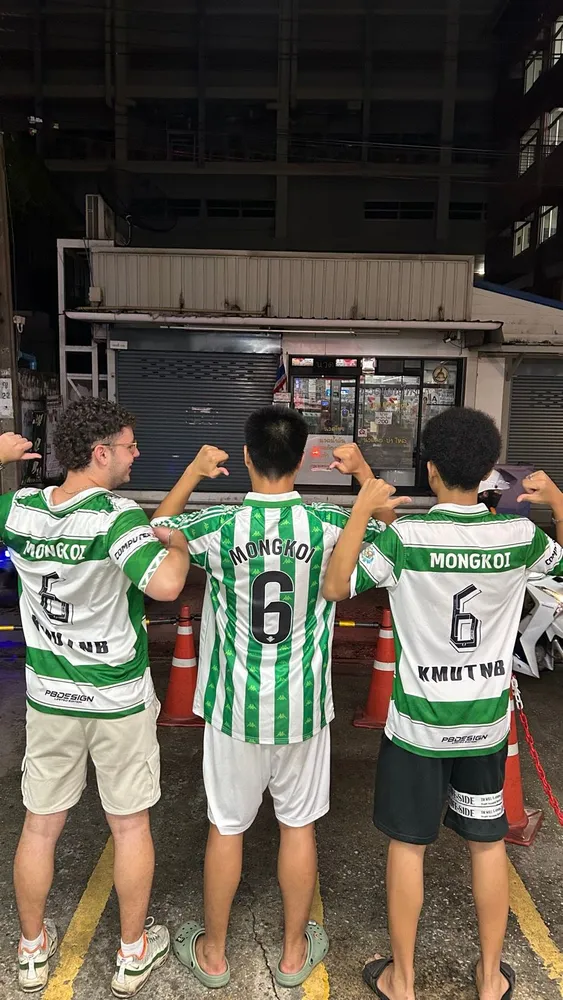 Three friends showing the backs of their football shirts