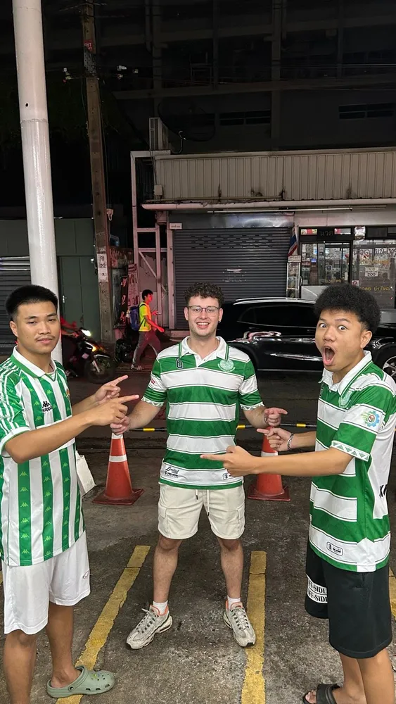 Friends in matching green football shirts beside the field